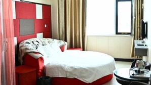 A hotel room with a bed, a desk, a chair, a TV, and a window with curtains. - Song Nantaiting Hotel (Junan County)