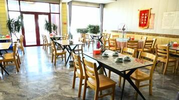 A dining area with tables and chairs, a red banner, and a door leading outside.
