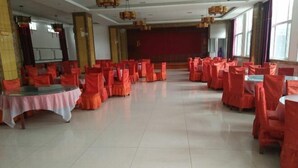 A spacious hall with rows of tables and chairs, large windows, and a stage area. - Song Nantaiting Hotel (Junan County)