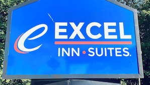 A blue sign with the logo and name of Excel Inn Suites. - Excel Inn & Suites (Fredericksburg)