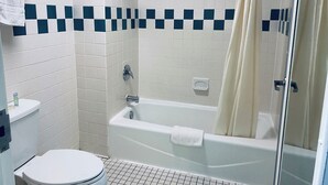 A bathroom with a bathtub, toilet, and shower curtain. - Excel Inn & Suites (Fredericksburg)