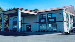 A modern building with a flat roof, large windows, and a covered entrance area. - Excel Inn & Suites (Fredericksburg)