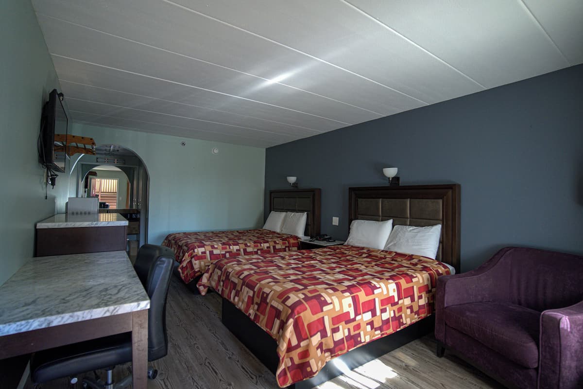 A room with two beds, a desk, and a purple armchair.