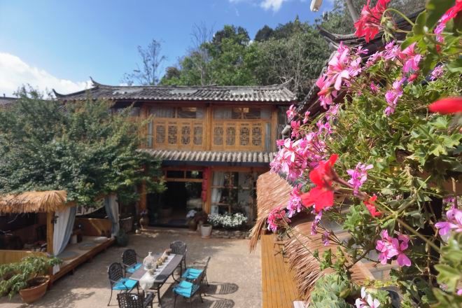 A traditional building with a thatched roof and a courtyard with a table and chairs.