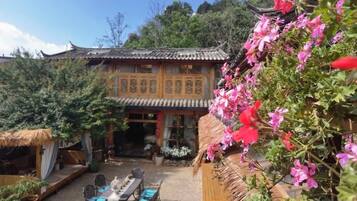 A traditional building with a thatched roof and a courtyard with a table and chairs.