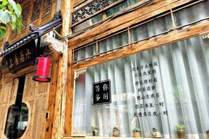 A traditional wooden building with a signboard and a window with a curtain. - Lijiang Shu He Shangshanruoshui Inn (Lijiang)