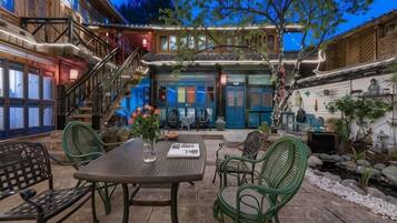 Un patio al aire libre con una mesa, sillas, una escalera y un edificio con puertas azules.
