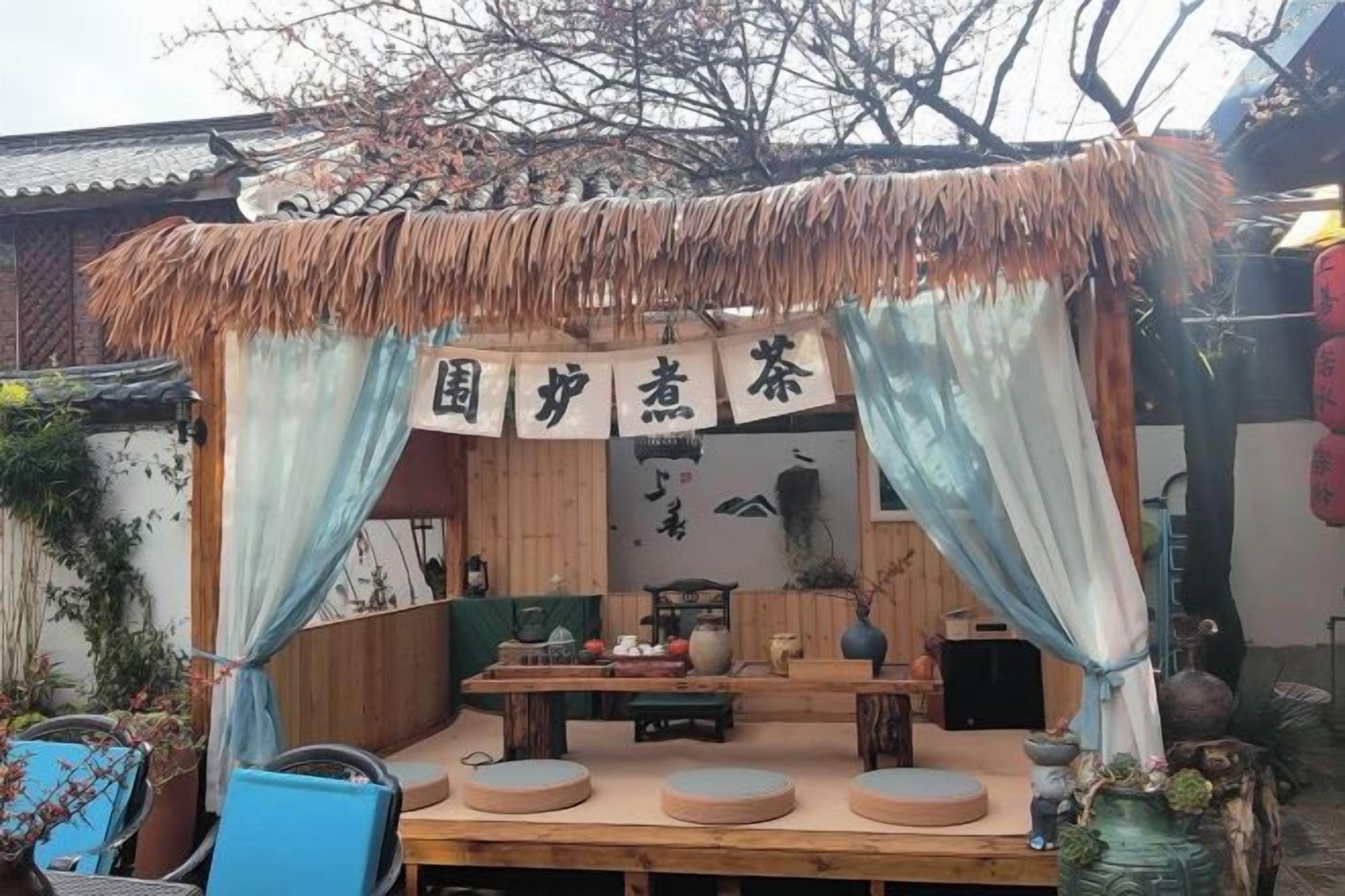 Een terras met buitenmeubels, een rieten dak en een bord met Chinese karakters.