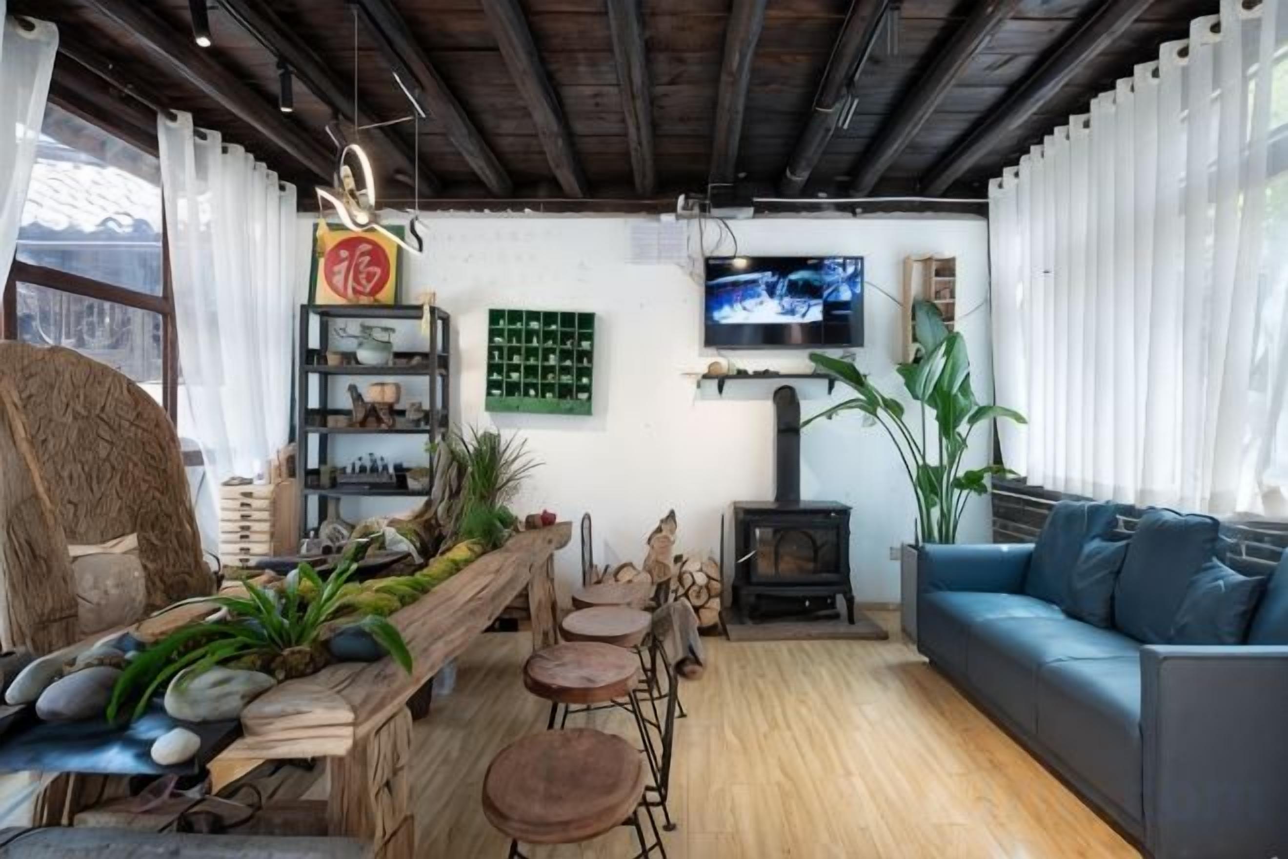 A cozy living room with a wooden bench, a sofa, and a fireplace. There are shelves with books and decorative items, and a television mounted on the wall.