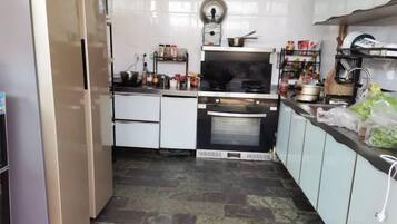 A kitchen with white cabinets, a stove, oven, and various kitchen items on the counter.
