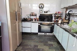 A kitchen with white cabinets, a stove, oven, and various kitchen items on the counter. - Lijiang Shu He Shangshanruoshui Inn (Lijiang)