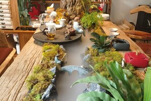 A dining table set with various dishes and drinks, surrounded by decorative plants and a miniature bridge. - Lijiang Shu He Shangshanruoshui Inn (Lijiang)