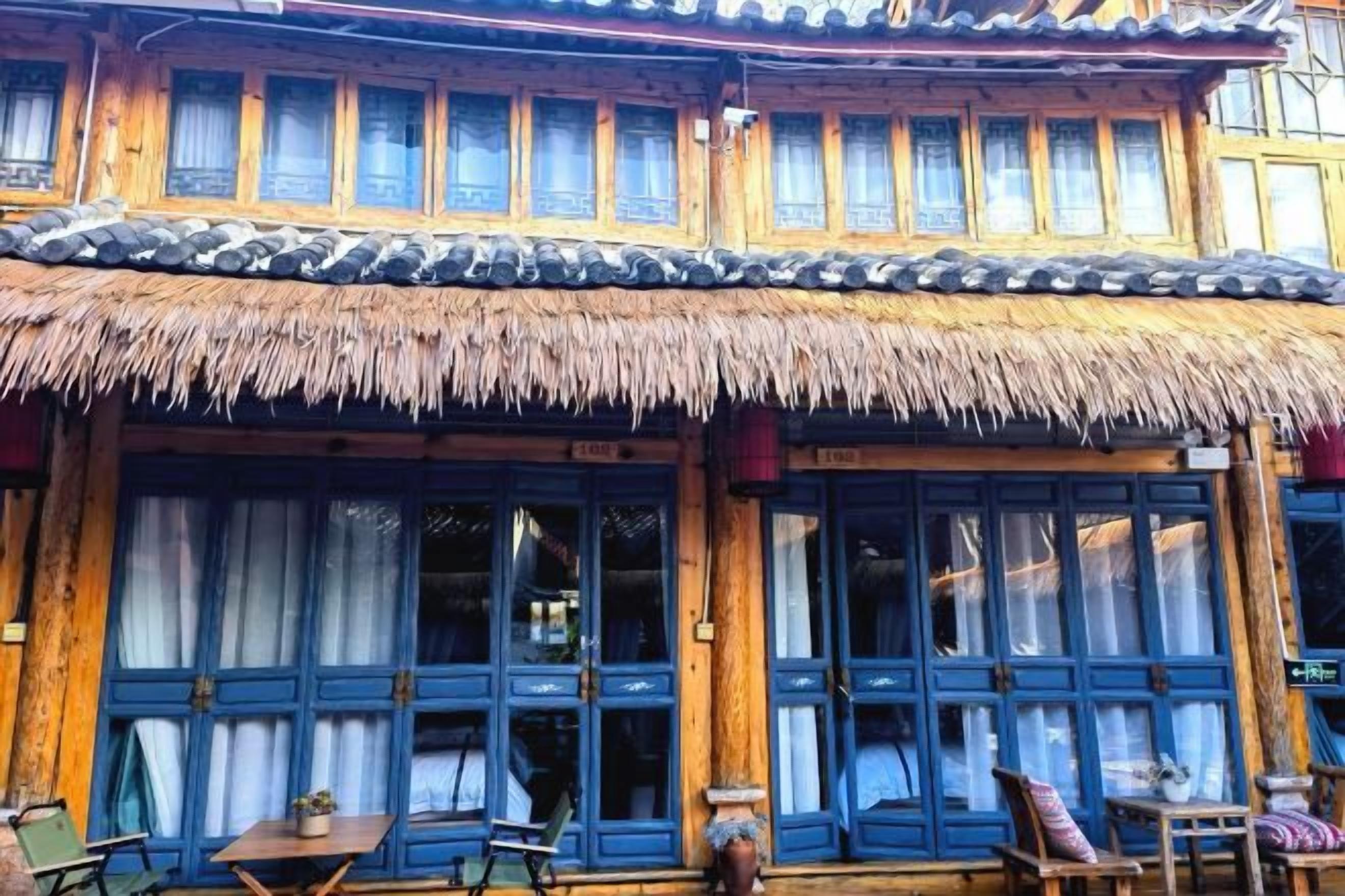 A traditional building with a thatched roof and blue-framed windows.