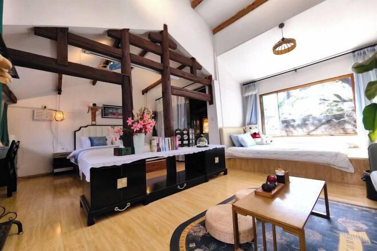 A bedroom with a bed, bedside table, and a window with curtains.