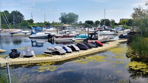 A marina with boats docked along the water's edge, featuring a small dock area with bags and gear.