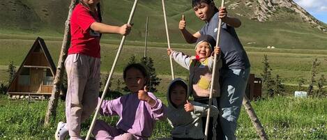 A group of people on a swing set in a mountainous area with a clear sky.