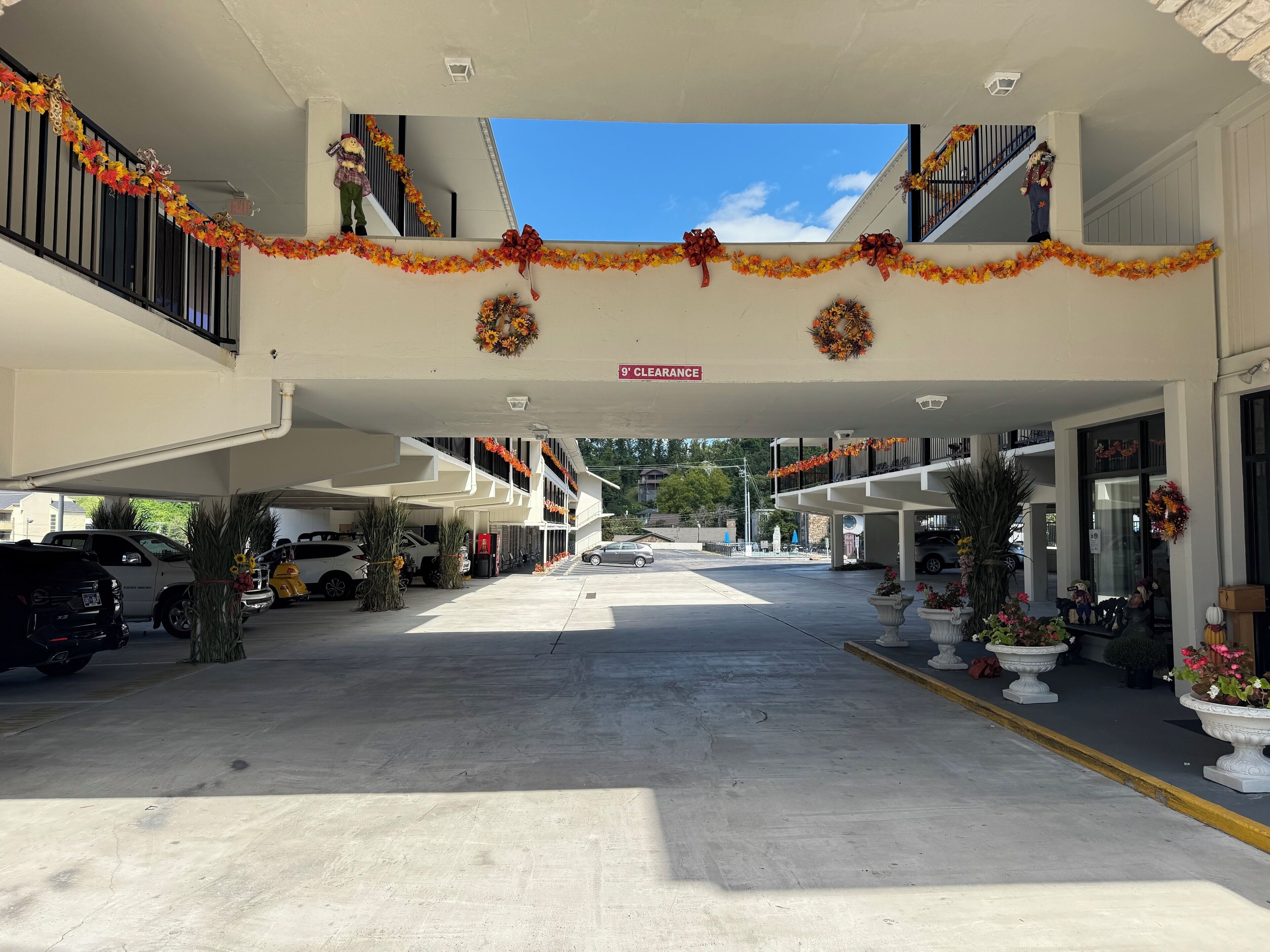 A hotel entrance with a covered parking area, decorated with autumn-themed garlands and wreaths.