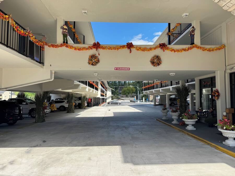 A hotel entrance with a covered parking area, decorated with autumn-themed garlands and wreaths.