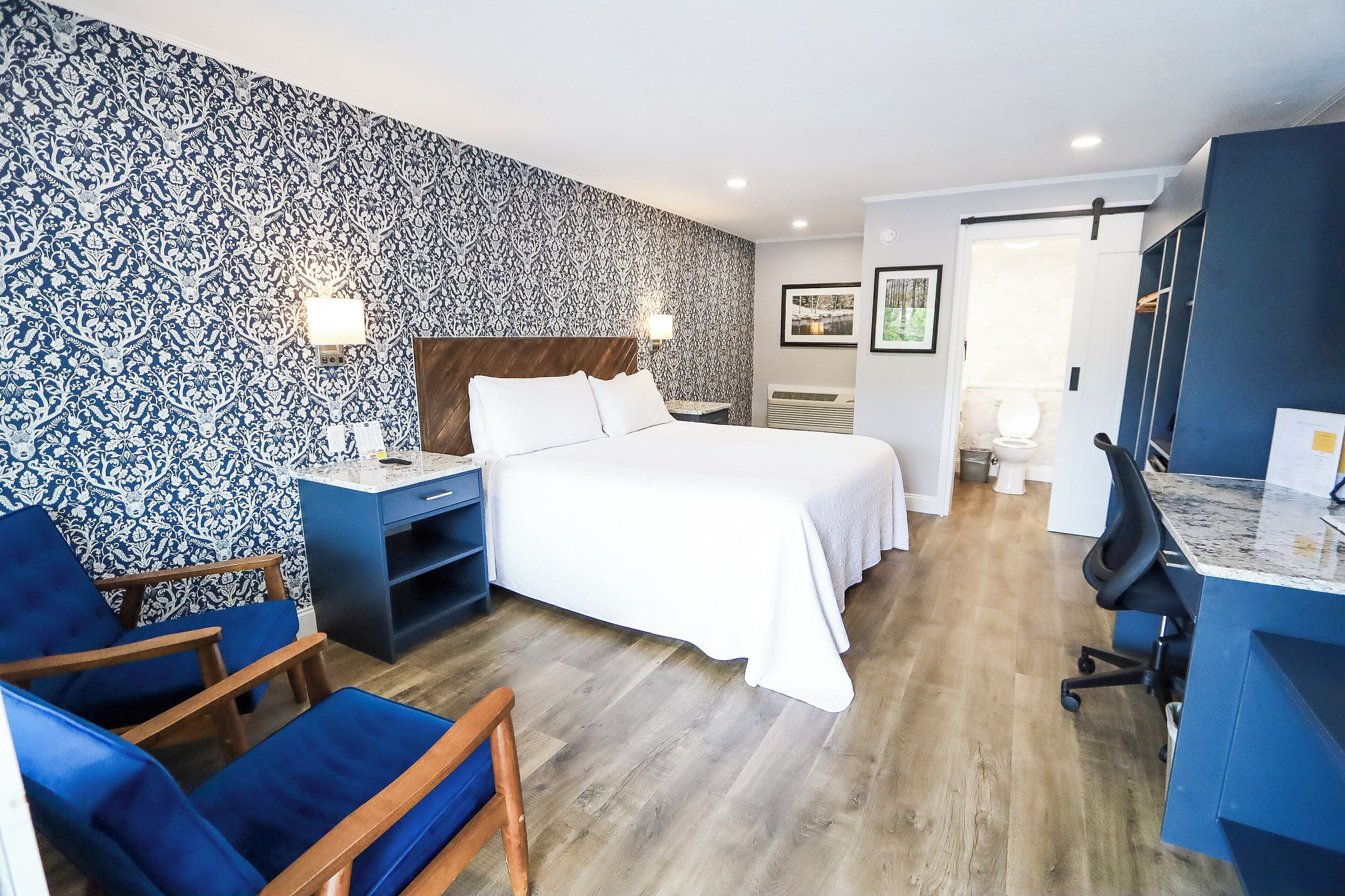 A hotel room with a bed, a desk, a chair, and a wardrobe.