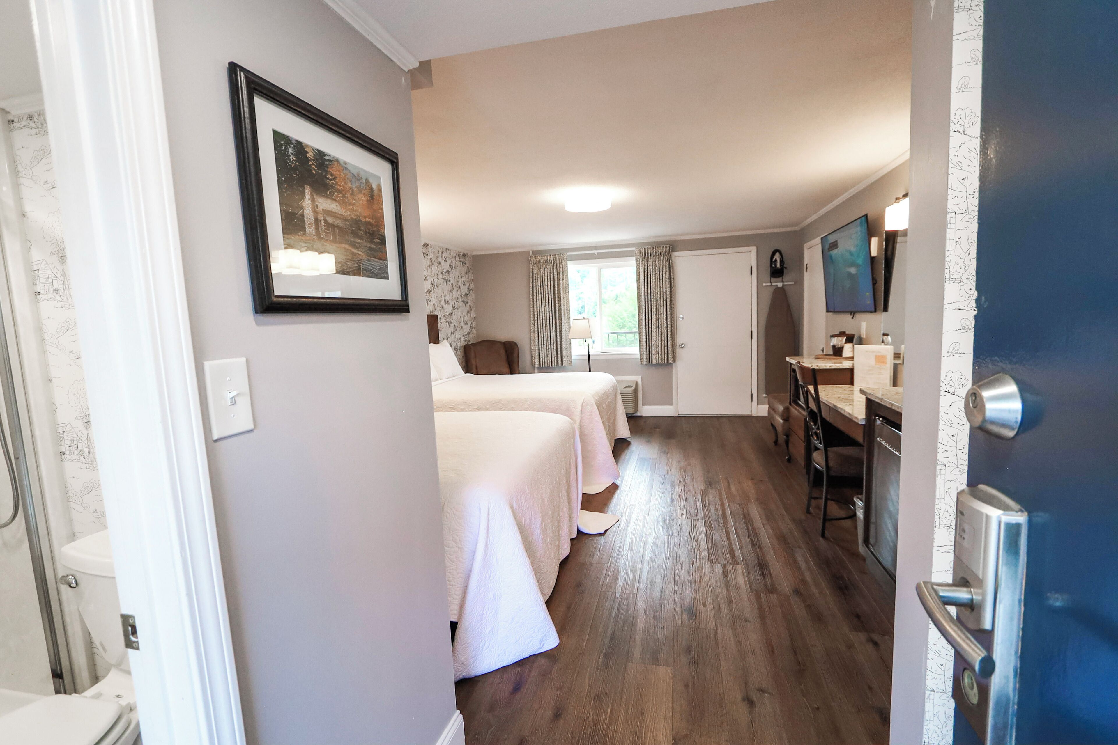 Ein Hotelzimmer mit zwei Betten, einem Badezimmer, einem Essbereich und einem Fernseher.