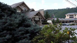 A lodge with a stone facade, a prominent sign, and a view of a parking area.