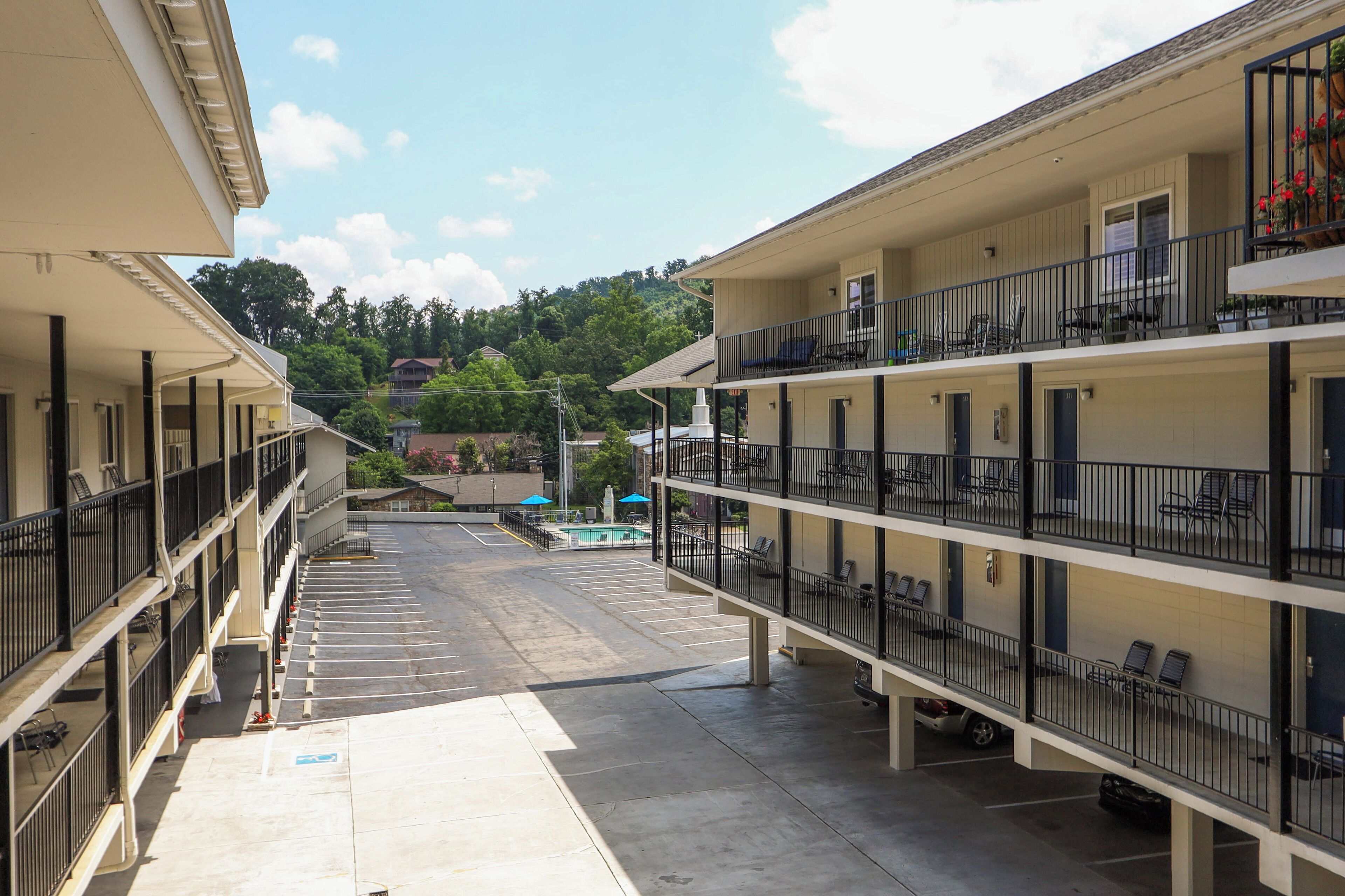 Un motel à plusieurs étages, doté de balcons, d’une piscine et d’un parking.