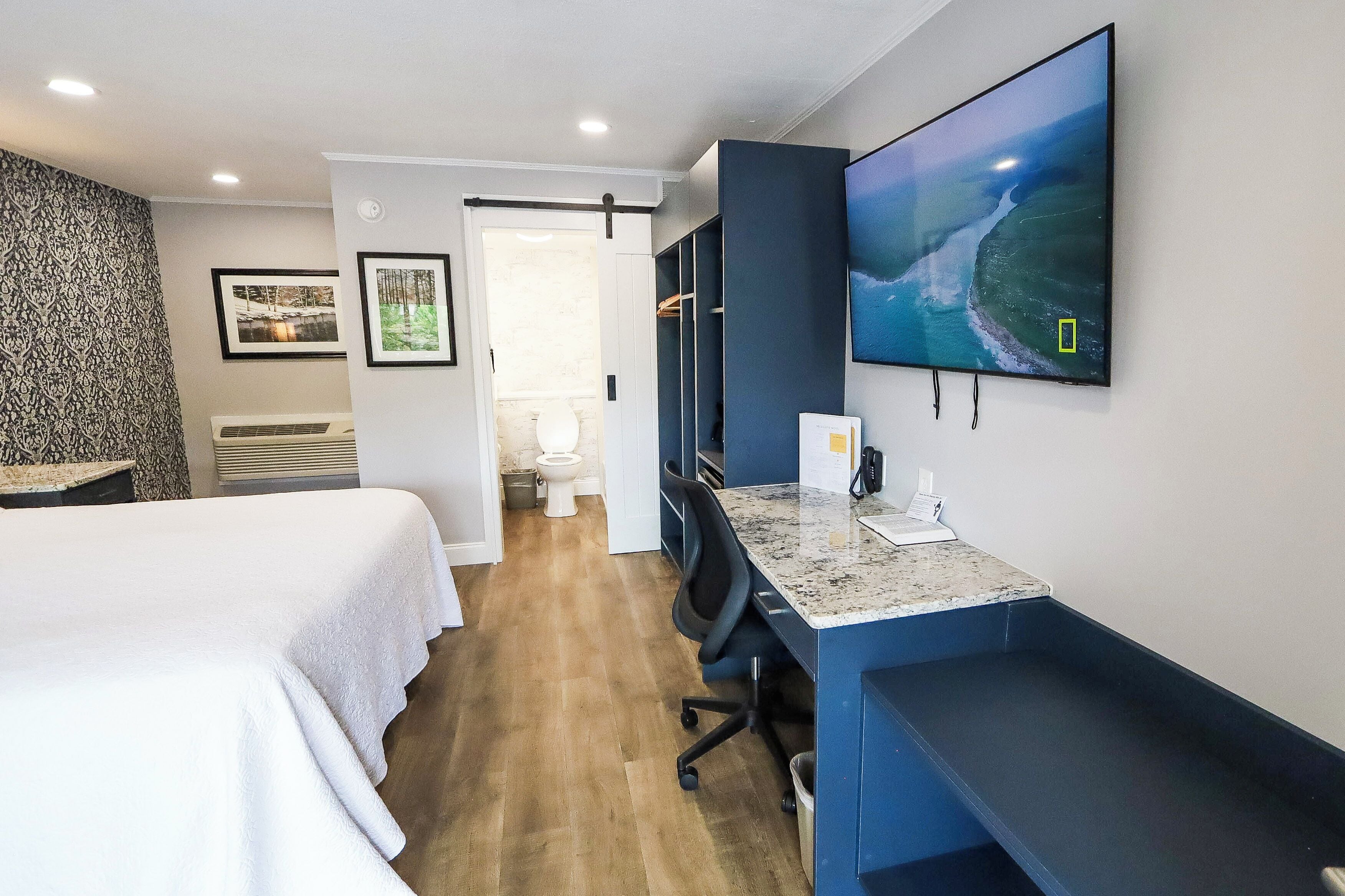 A hotel room with a bed, desk, and TV.