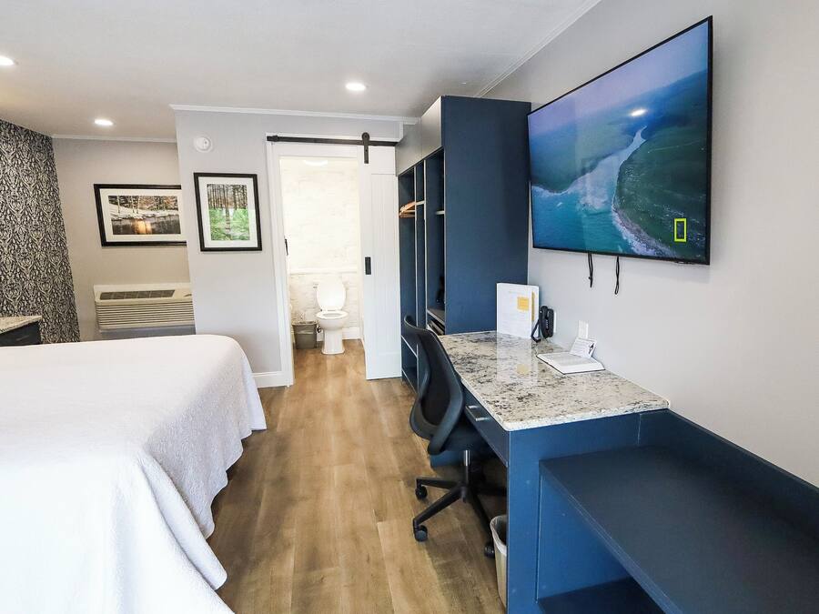 A hotel room with a bed, desk, and TV.