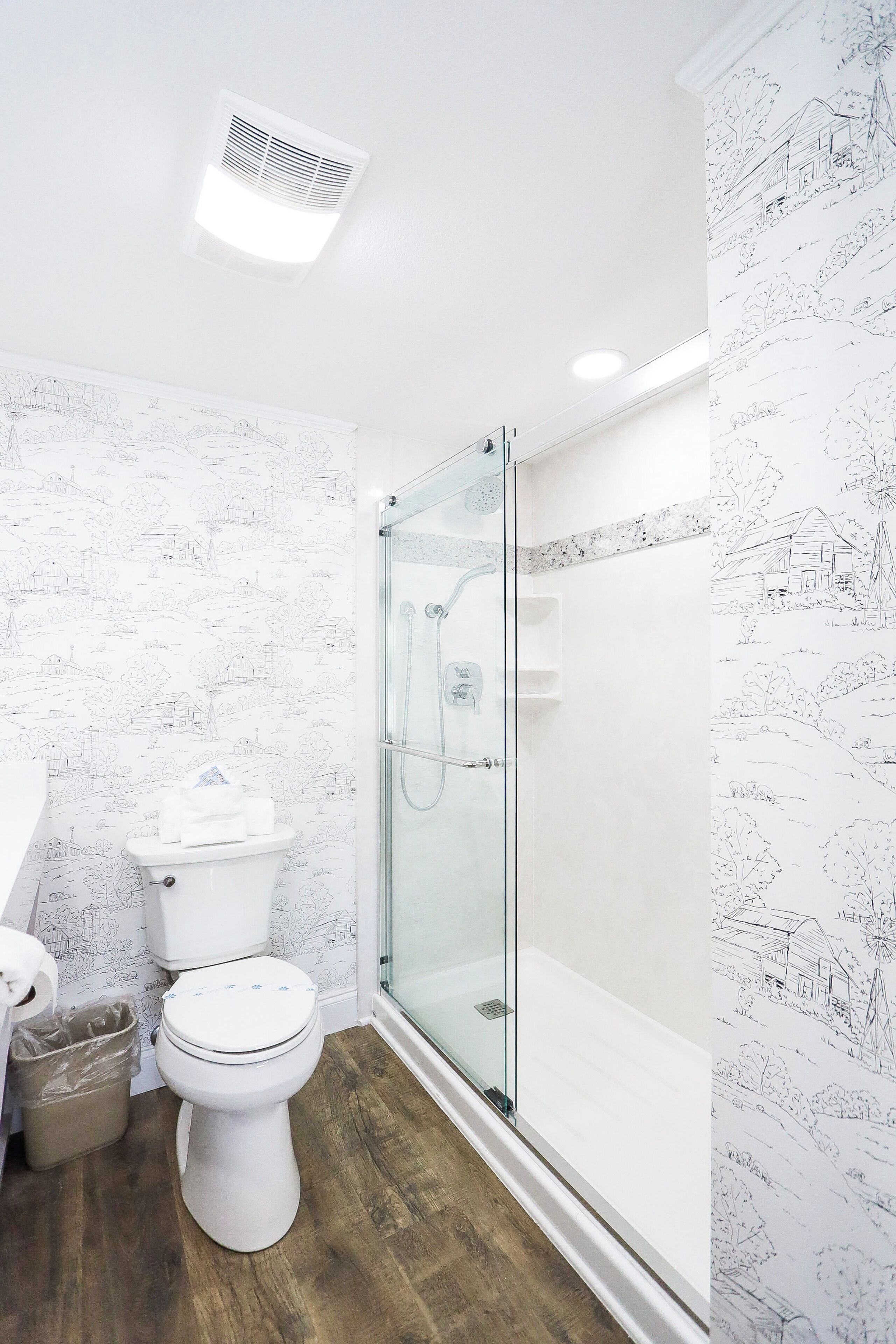 A modern bathroom with a toilet, shower, and glass-enclosed shower stall.