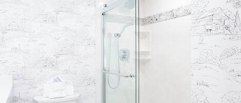 A modern bathroom with a toilet, shower, and glass-enclosed shower stall.