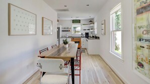 A modern kitchen with a wooden dining table, chairs, and a central island.