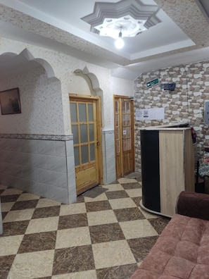 A lobby with a checkered floor, a reception desk, and a staircase leading to an upper level. - mirana mayotte hostel 47 (Ghardaia)