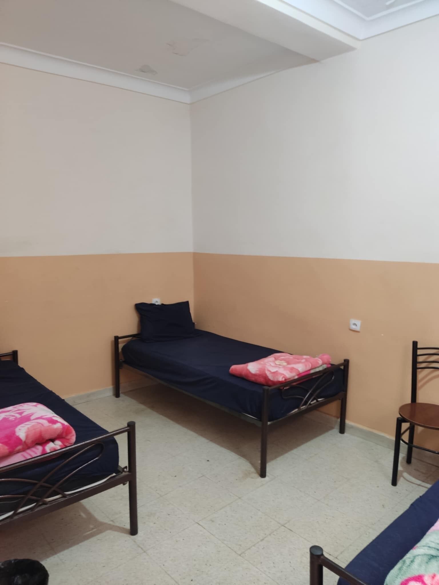 Un dormitorio con dos camas individuales, una silla y una mesita.