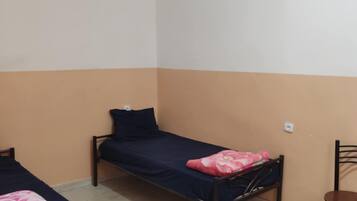 Un dormitorio con dos camas individuales, una silla y una mesita.