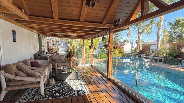 Un espace extérieur abrité comprenant une piscine, une terrasse en bois et des sièges.
