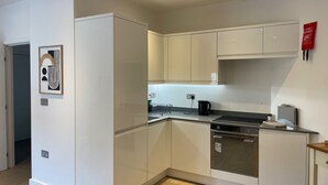 A modern kitchen with white cabinetry, a stainless steel oven, and a black kettle. - Spacious 1 Bedroom Apartment in St Albans (St Albans)