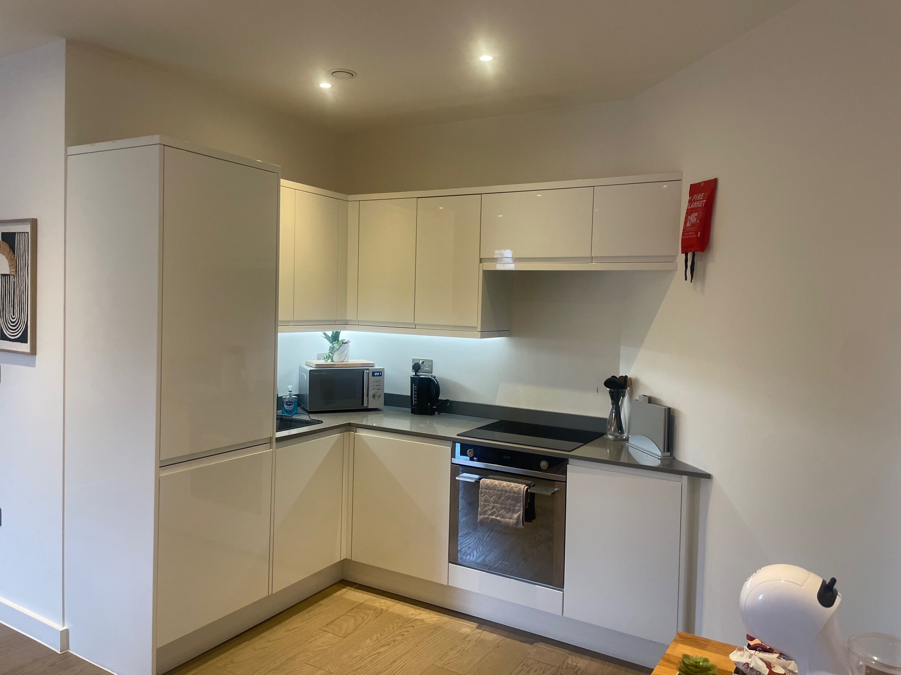 A modern kitchen with white cabinets, a microwave, a coffee maker, and a built-in oven.