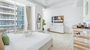 Quarto de hotel moderno com uma cama grande, televisão, escrivaninha e varanda com vista para a cidade.