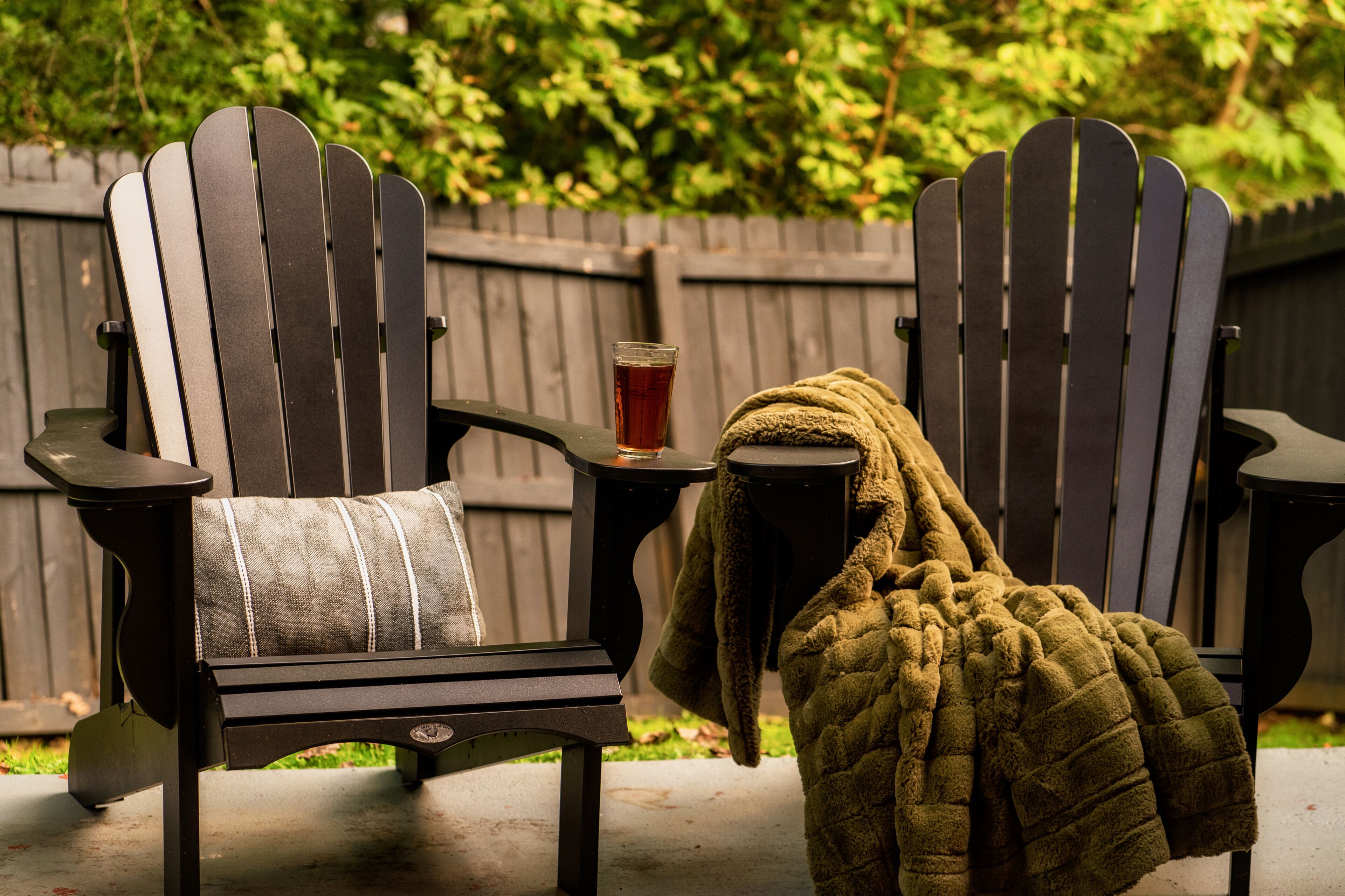 Deux fauteuils Adirondack, une boisson et une couverture sur une terrasse.