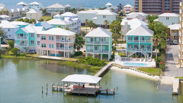 Una zona residencial costera con casas coloridas, un muelle y un edificio grande al fondo.