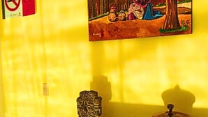 Ein Zimmer mit einem Holztisch, einer kleinen Statue und einem Gemälde an der Wand.
