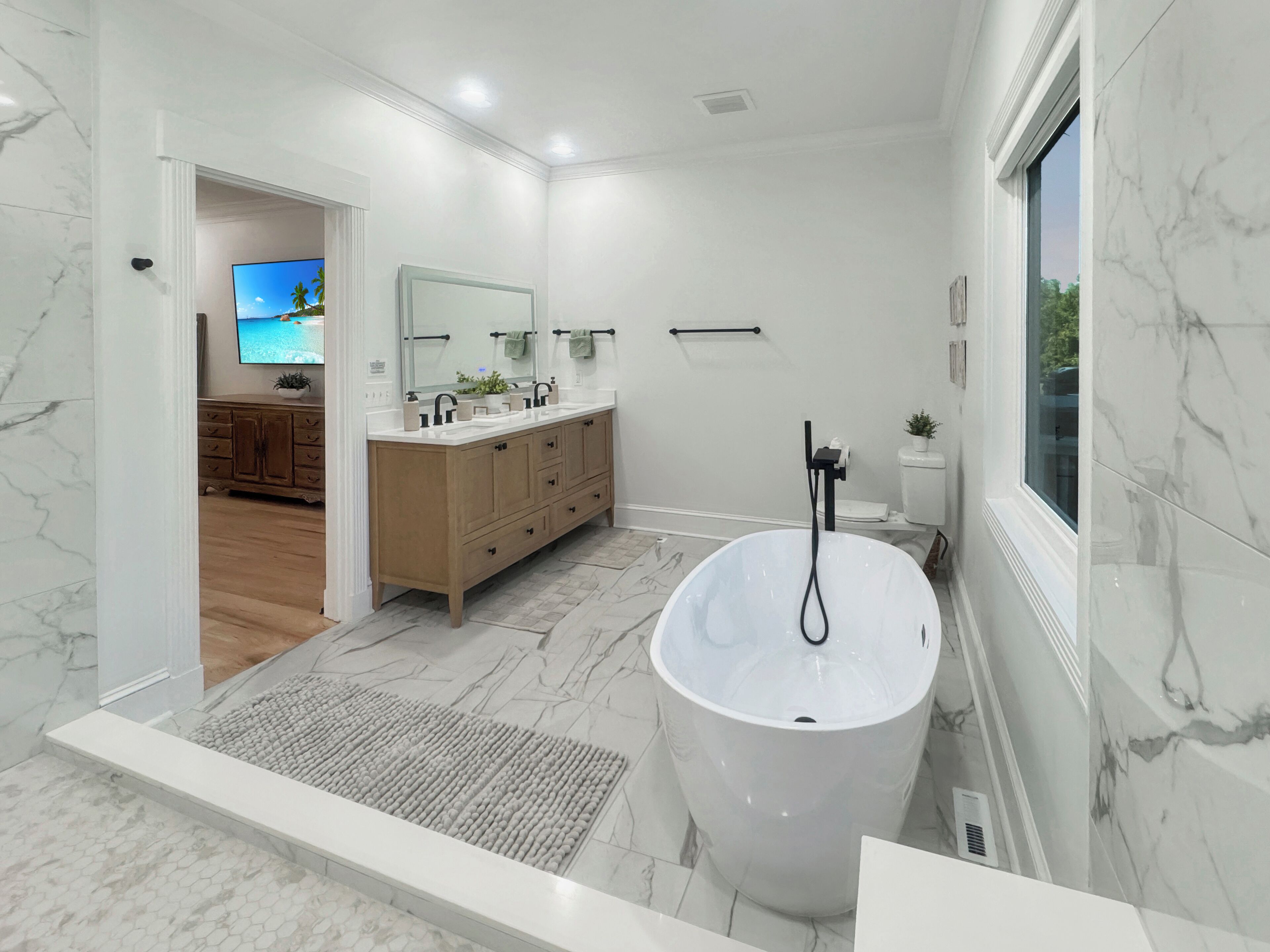 Une salle de bain moderne avec une grande baignoire, un meuble-lavabo avec un miroir et des toilettes.