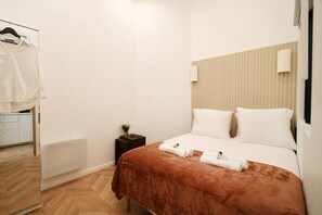 Ein Hotelzimmer mit einem Bett, einem Nachttisch mit Pflanze, einem Heizkörper und einem Handtuch.