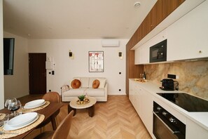 Une cuisine moderne équipée d’un four à micro-ondes, d’un four traditionnel et d’un coin repas avec une table dressée pour deux personnes.