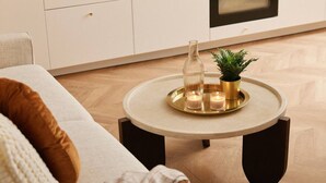 Una sala de estar moderna con una mesita de centro redonda, una planta en maceta y velas.
