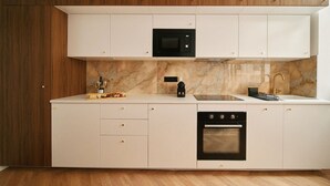 Una cocina moderna con armarios blancos, un microondas negro, horno empotrado y salpicadero de mármol.