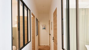 A hallway with wooden flooring, white walls, and doors with black frames.