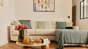 A living room with a sofa, a coffee table with breakfast items, and a painting on the wall.
