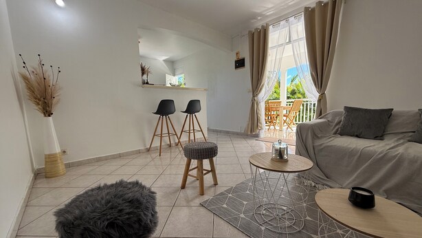 A modern living room with a sofa, a coffee table, and two bar stools. - Villa apartment with private garden – quiet – 4 guests – Sainte-Anne (Sainte-Anne)