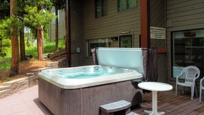 Un jacuzzi en una terraza de madera con una mesita y dos sillas.